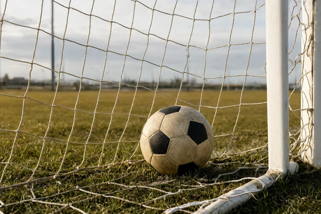 Gol de campo de treino com rede vazia e uma bola parada dentro da rede